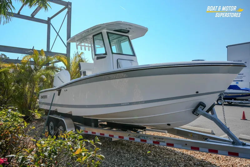 Slide: The Image of 2026 Blackfin 242 HB boat on trailer at dealership, surrounded by palm trees. - 6