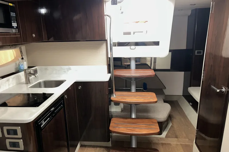 Slide: The Image of 2019 Sea Ray Sundancer 350 Coupe interior with modern kitchen and wooden stairs. - 18