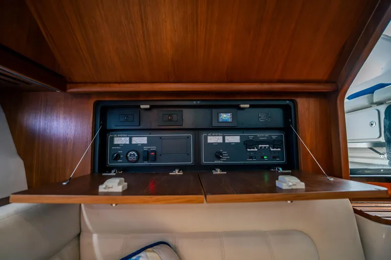 Slide: The Image of 2005 Tiara Yachts 3200 Open electrical panel with wooden cabinetry and control switches. - 10