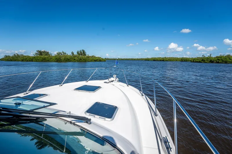 Slide: The Image of 2005 Tiara Yachts 3200 Open cruising on a serene river under a clear blue sky. - 26