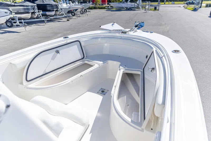 Slide: The Image of 2022 Edgewater 245CC boat interior with open storage compartments in a marina setting. - 10