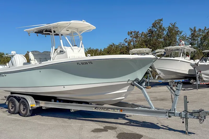 Slide: The Image of 2022 Edgewater 245CC boat on trailer, parked outdoors under clear blue sky. - 15