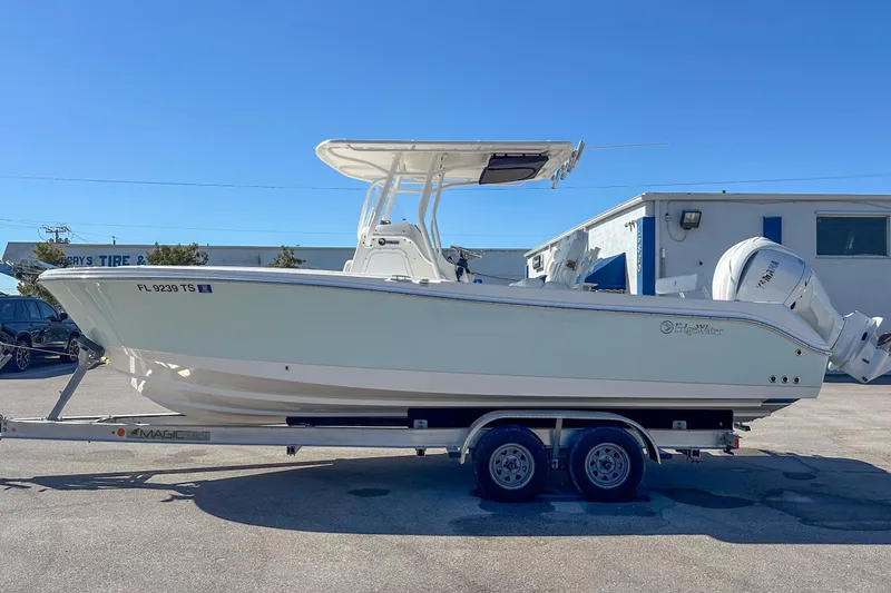 Slide: The Image of 2022 Edgewater 245CC boat on trailer, parked outdoors under clear blue sky. - 18