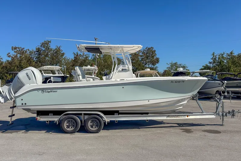 Slide: The Image of 2022 Edgewater 245CC boat on trailer, parked outdoors under clear blue sky. - 21