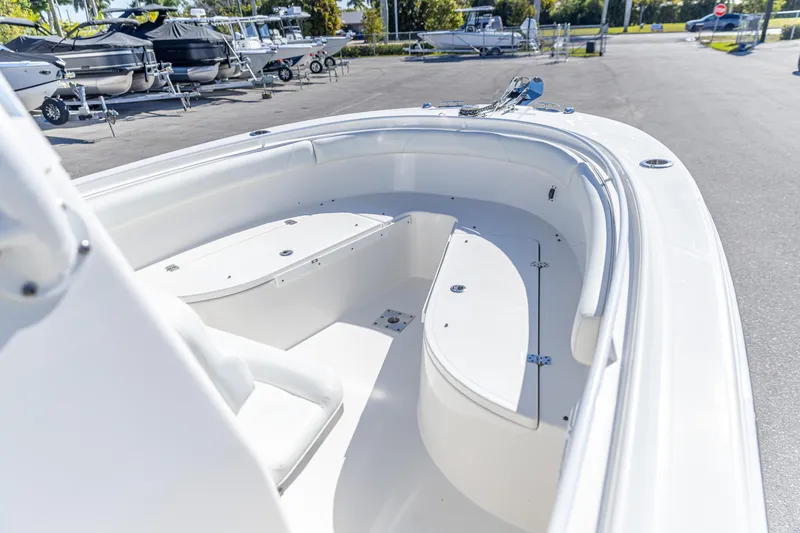Slide: The Image of 2022 Edgewater 245CC boat interior with seating and storage, parked among other boats. - 22