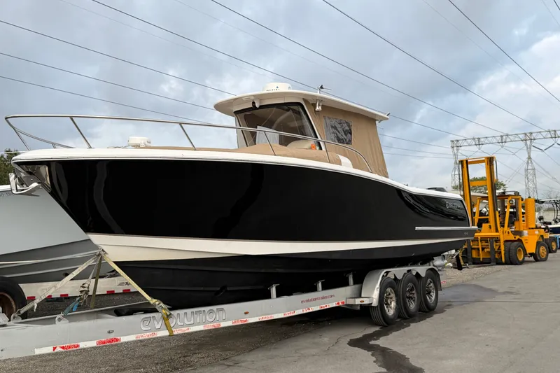 Slide: The Image of 2015 Belzona 32 Walkaround boat on trailer, black hull, parked outdoors. - 14