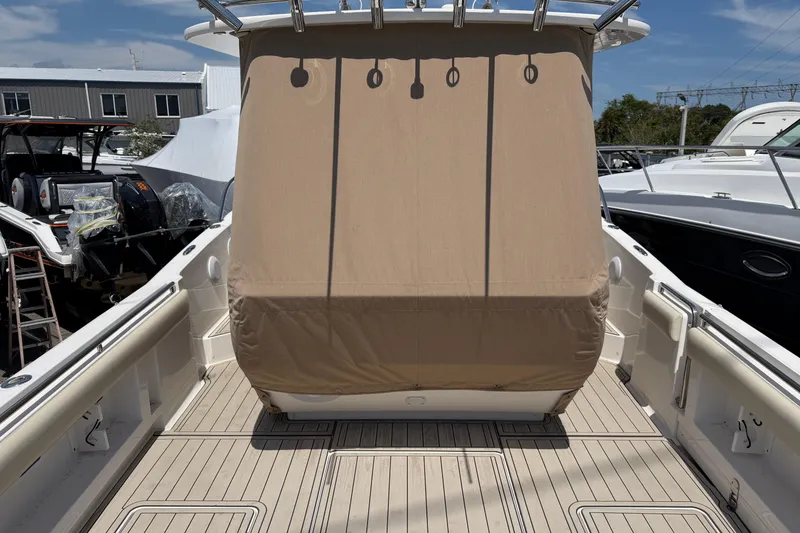 Slide: The Image of 2015 Belzona 32 Walkaround boat with beige cover, docked in a marina. - 15