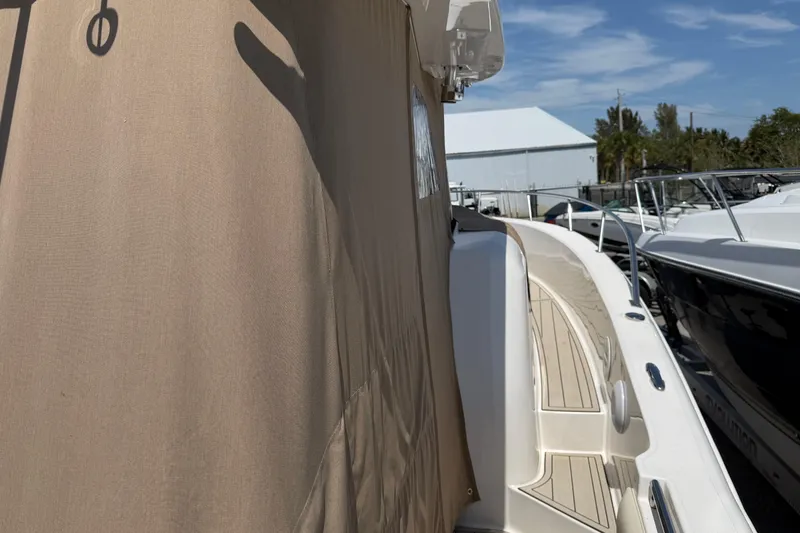 Slide: The Image of 2015 Belzona 32 Walkaround boat with beige cover, docked under clear blue sky. - 16