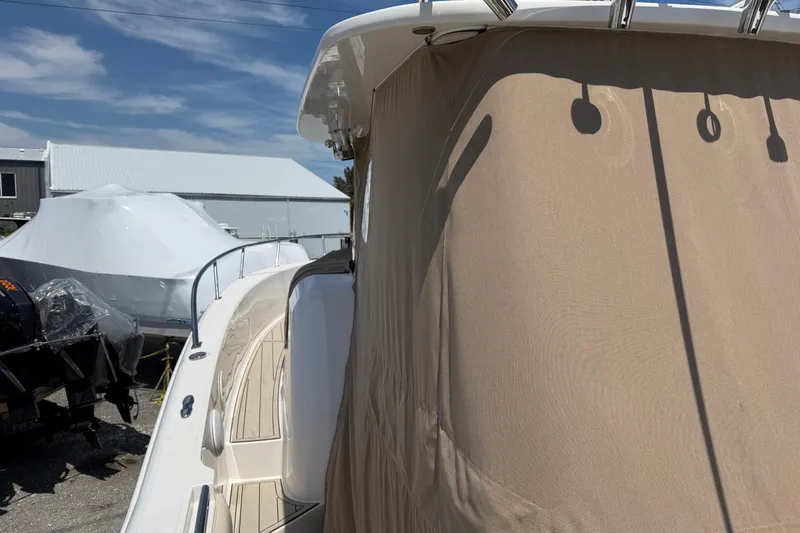 Slide: The Image of 2015 Belzona 32 Walkaround boat with beige cover, docked outdoors under blue sky. - 17