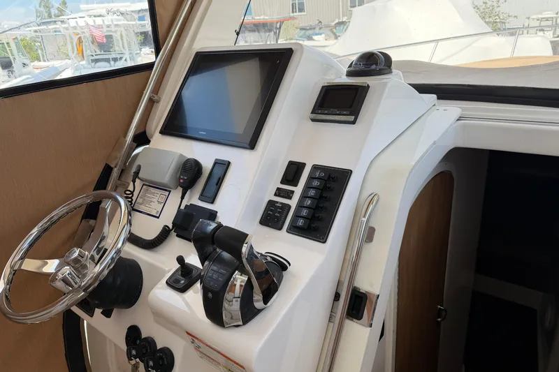 Slide: The Image of Control panel of a 2015 Belzona 32 Walkaround boat with steering wheel and navigation equipment. - 18
