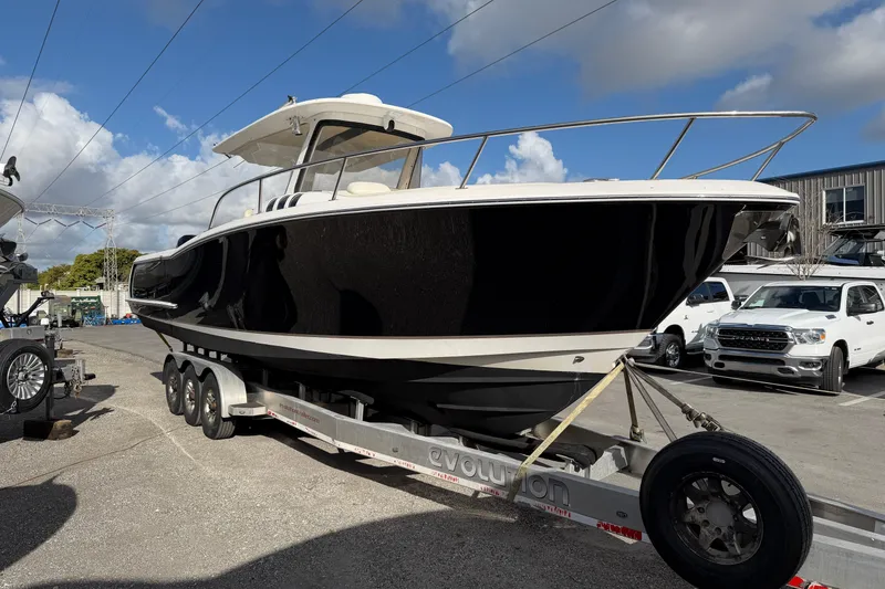 Slide: The Image of 2015 Belzona 32 Walkaround boat on trailer, parked outdoors under a blue sky. - 3