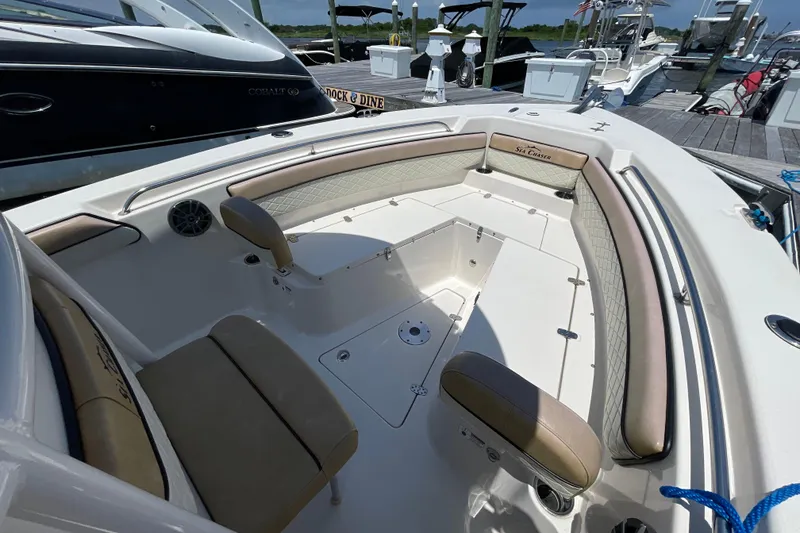 Slide: The Image of 2023 Sea Chaser 24 HFC boat interior with cushioned seating at a marina. - 3