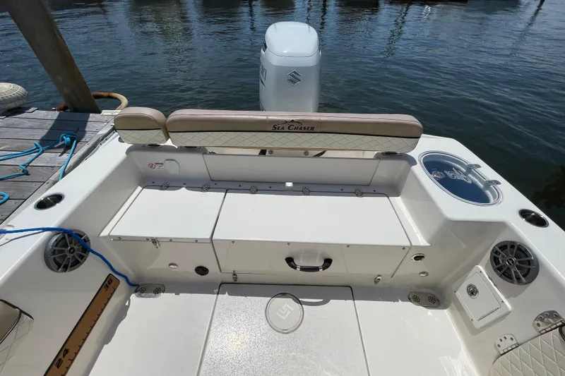 Slide: The Image of 2023 Sea Chaser 24 HFC boat interior with seating and storage, docked by the water. - 31