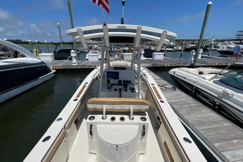 Slide: The Image of 2023 Sea Chaser 24 HFC boat docked at marina, featuring helm and seating area. - 38