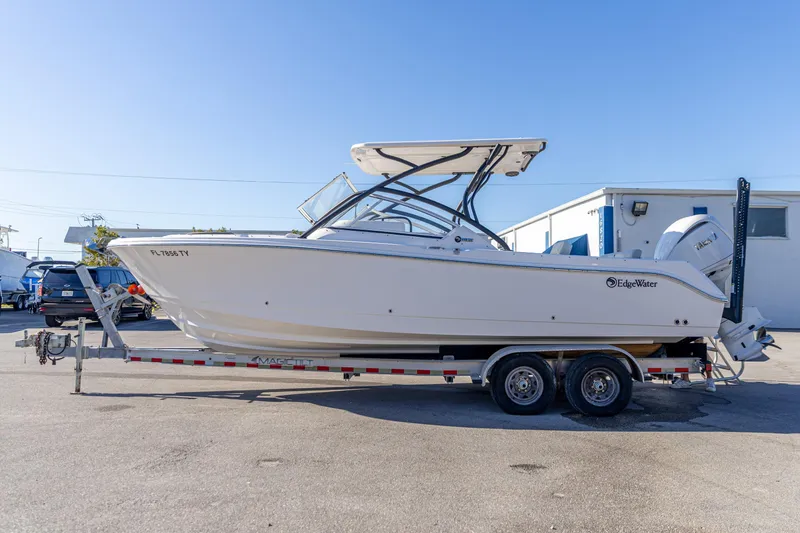 Slide: The Image of 2025 Edgewater 248CX Crossover boat on trailer, parked outdoors under clear blue sky. - 21