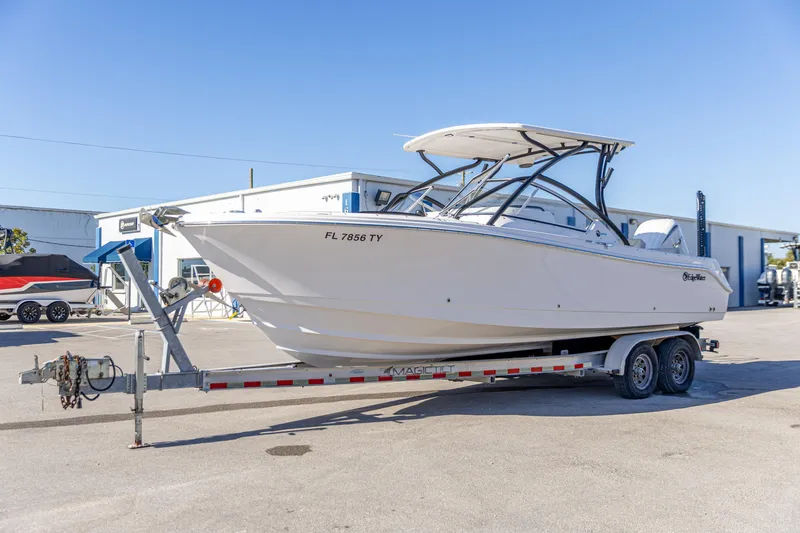 Slide: The Image of 2025 Edgewater 248CX Crossover boat on trailer, parked outdoors under clear blue sky. - 9