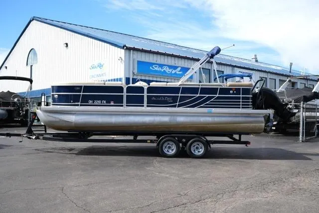The Image of 2012 South Bay 722CR pontoon boat on trailer, parked outside a marine dealership. - 1