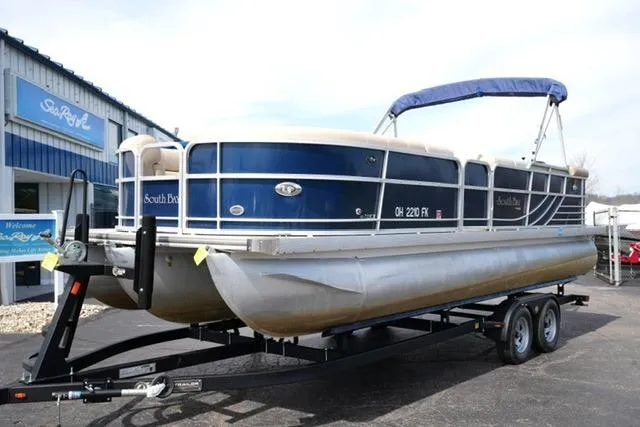 Slide: The Image of 2012 South Bay 722CR pontoon boat on trailer, parked outside dealership. - 2
