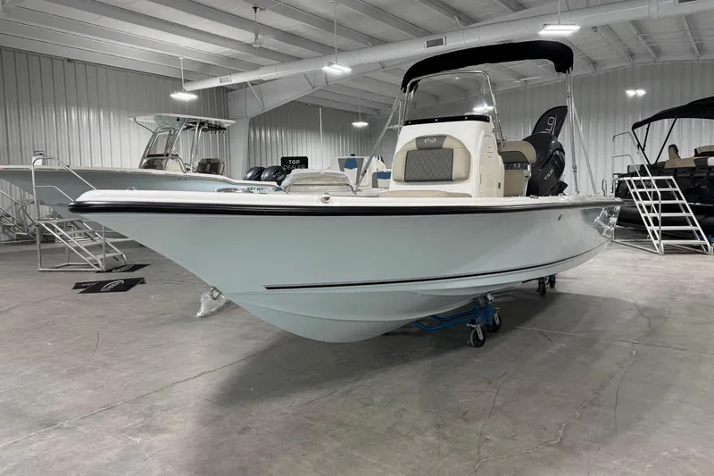 Slide: The Image of 2026 Key West 210 Bay Reef boat displayed in a showroom, featuring sleek design and modern amenities. - 2