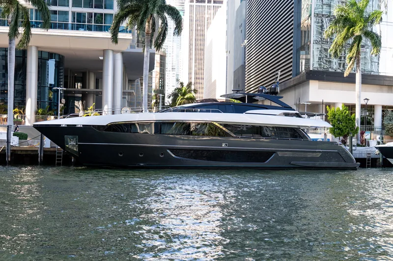 Slide: The Image of Luxury 2020 Riva 100' Corsaro yacht docked by modern waterfront buildings. - 2
