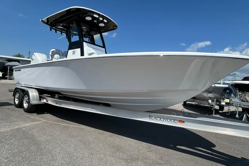 Slide: The Image of 2026 Sportsman Masters 247OE Bay Boat on Blackwood trailer, parked outdoors. - 5