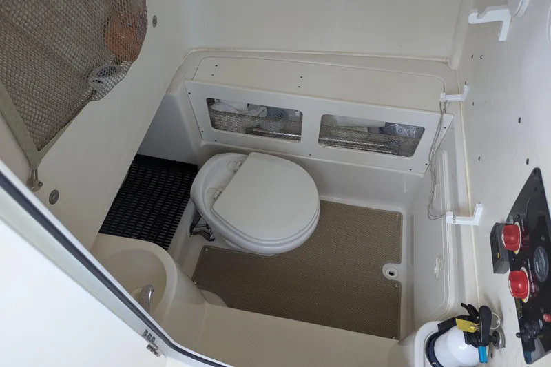 Slide: The Image of 2018 Sailfish 270 CC boat interior with compact marine toilet and control panel. - 16
