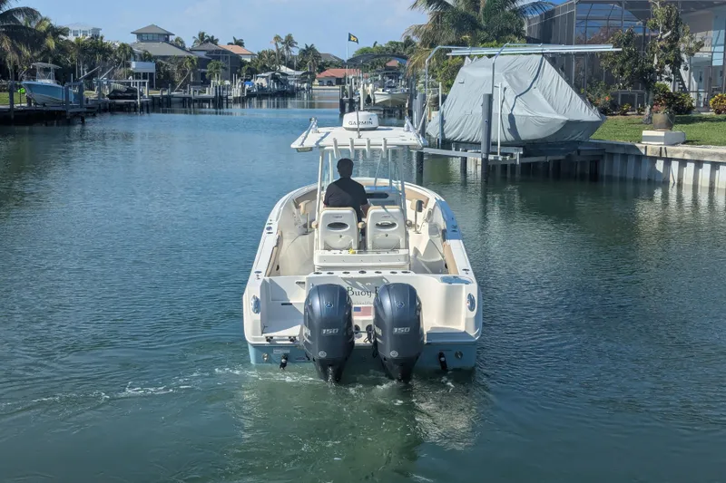 Slide: The Image of 2018 Sailfish 270 CC boat navigating a calm canal with twin engines. - 4