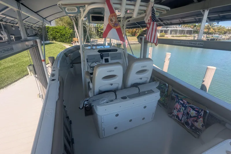 Slide: The Image of 2018 Sailfish 270 CC boat docked, featuring dual flags and a spacious cockpit. - 5