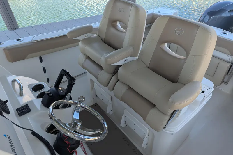 Slide: The Image of 2018 Sailfish 270 CC boat interior with dual captain's chairs and steering wheel. - 8
