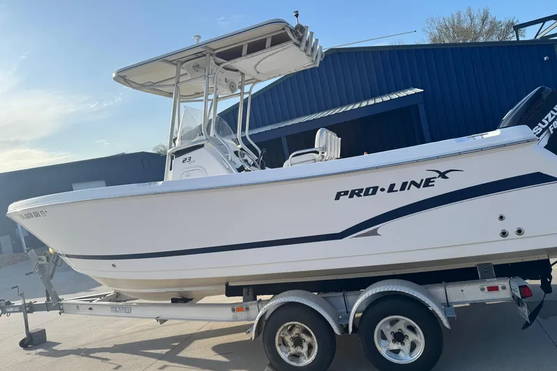 Slide: The Image of 2007 PROLINE 23 Sport boat on trailer, parked outdoors near a blue building. - 3