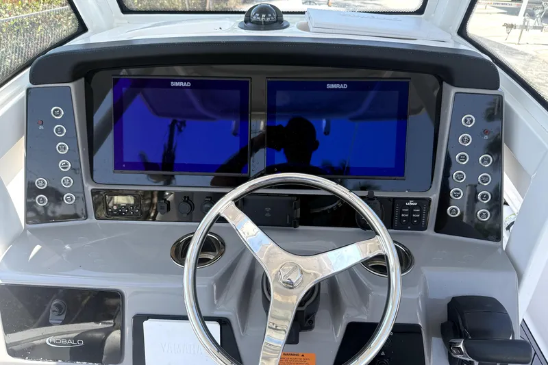Slide: The Image of 2022 Robalo 266 Cayman boat dashboard with dual Simrad displays and steering wheel. - 10