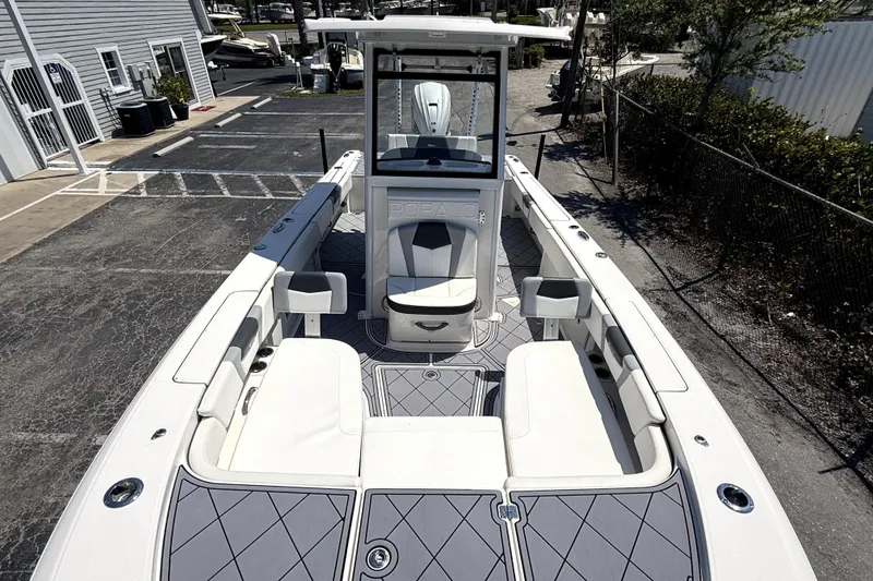 Slide: The Image of 2022 Robalo 266 Cayman boat interior with seating and console, parked at a marina. - 14
