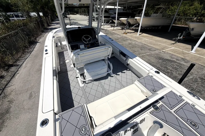 Slide: The Image of 2022 Robalo 266 Cayman boat interior with helm and seating, parked in a marina. - 6