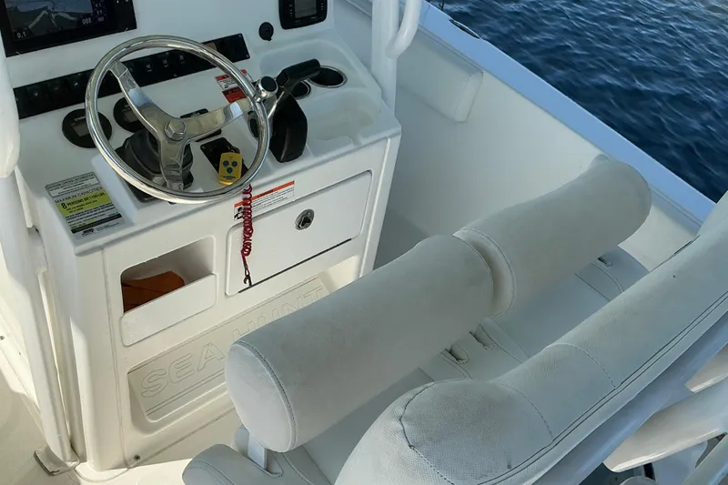 Slide: The Image of 2016 Sea Hunt Ultra 225 boat cockpit with steering wheel and cushioned seating. - 10