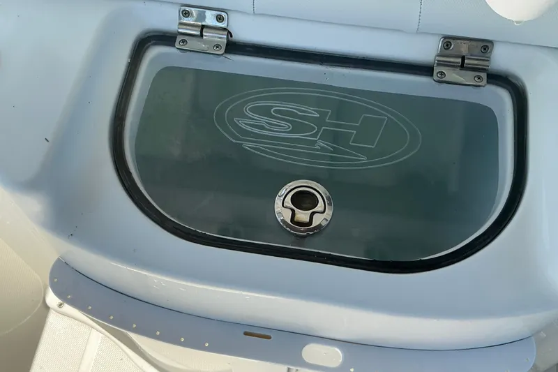 Slide: The Image of 2016 Sea Hunt Ultra 225 boat compartment with SH logo and secure latch. - 17