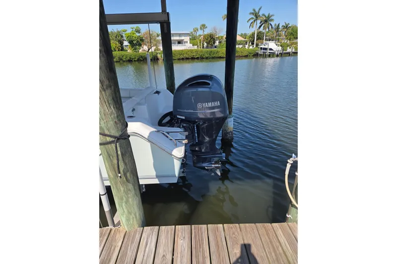Slide: The Image of 2016 Sea Hunt Ultra 225 with Yamaha outboard motor docked by waterfront. - 2