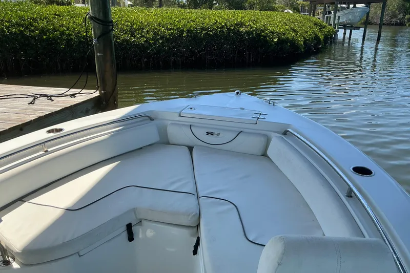 Slide: The Image of 2016 Sea Hunt Ultra 225 boat interior with white seating, docked by calm waters. - 22