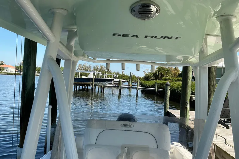 Slide: The Image of 2016 Sea Hunt Ultra 225 boat docked by a serene waterfront. - 23
