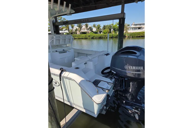 Slide: The Image of 2016 Sea Hunt Ultra 225 boat with Yamaha engine docked by a scenic waterfront. - 4