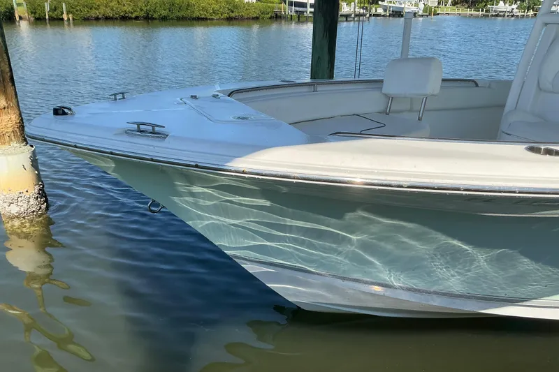 Slide: The Image of 2016 Sea Hunt Ultra 225 boat docked on calm water, reflecting sunlight. - 6