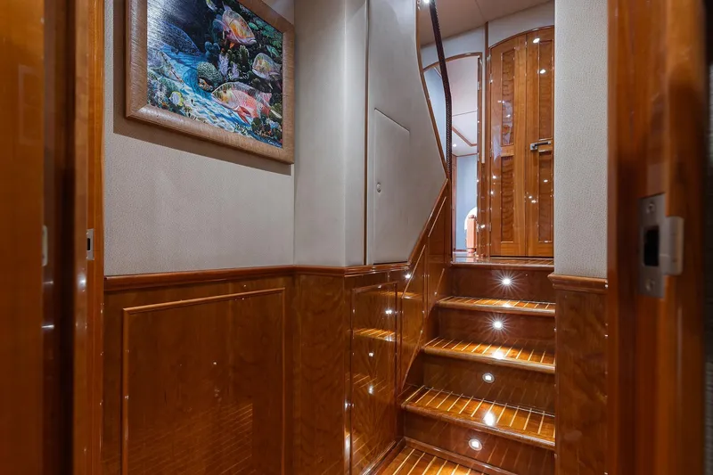 Slide: The Image of Luxurious wooden staircase interior on 2016 Viking 82 Sky Bridge yacht, featuring elegant artwork. - 21