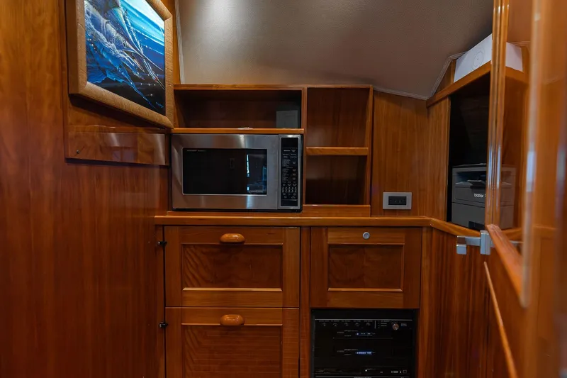 Slide: The Image of Wooden interior of 2016 Viking 82 Sky Bridge yacht with microwave and storage cabinets. - 22