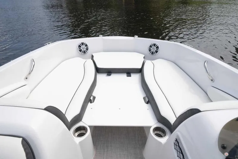 Slide: The Image of Manufacturer Provided Image: 2026 Stingray 182 SC boat interior with white seating and cup holders on calm water. - 11