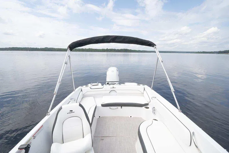 Slide: The Image of Manufacturer Provided Image: 2026 Stingray 182 SC boat interior with seating, bimini top, and serene lake view. - 13