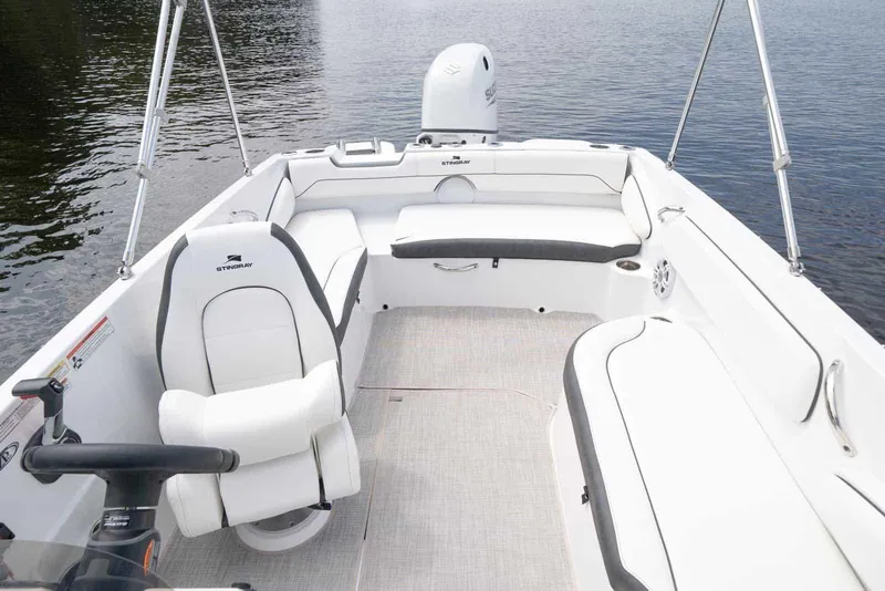 Slide: The Image of Manufacturer Provided Image: 2026 Stingray 182 SC boat interior with white seating and steering, on calm water. - 14