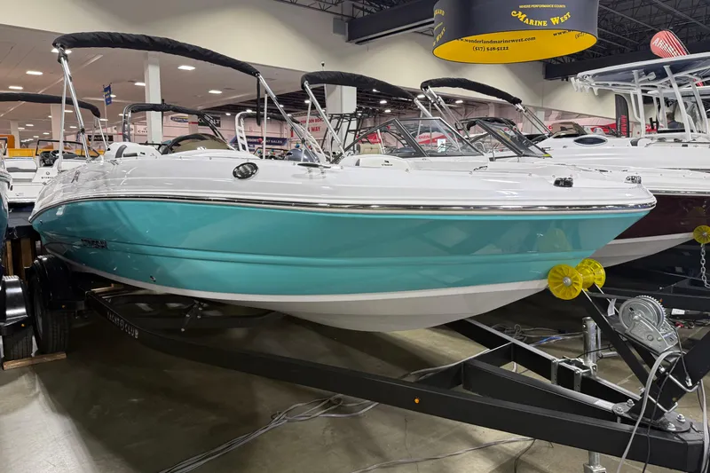 Slide: The Image of 2026 Stingray 182 SC boat with teal hull on display indoors. - 6