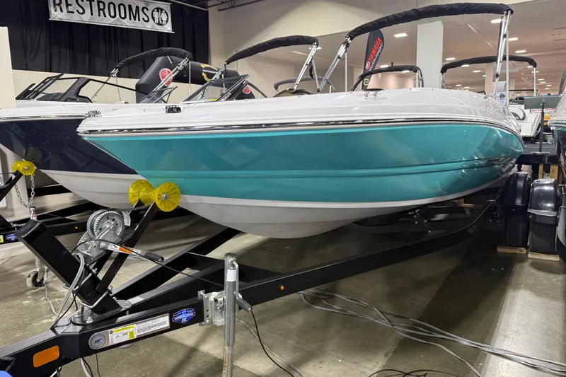 Slide: The Image of 2026 Stingray 182 SC boat on display indoors, teal and white design, on a trailer. - 7