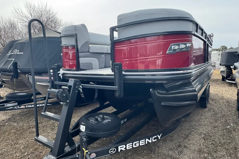 The Image of 2025 Regency 230 DL3 pontoon boat on trailer, red and gray exterior. - 1