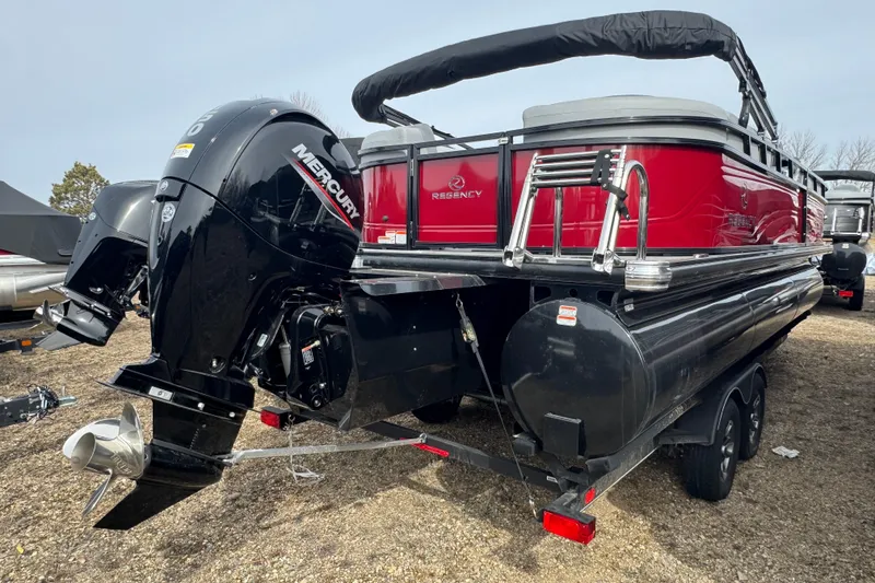 Slide: The Image of 2025 Regency 230 DL3 pontoon boat with Mercury outboard engine, parked on a trailer. - 3