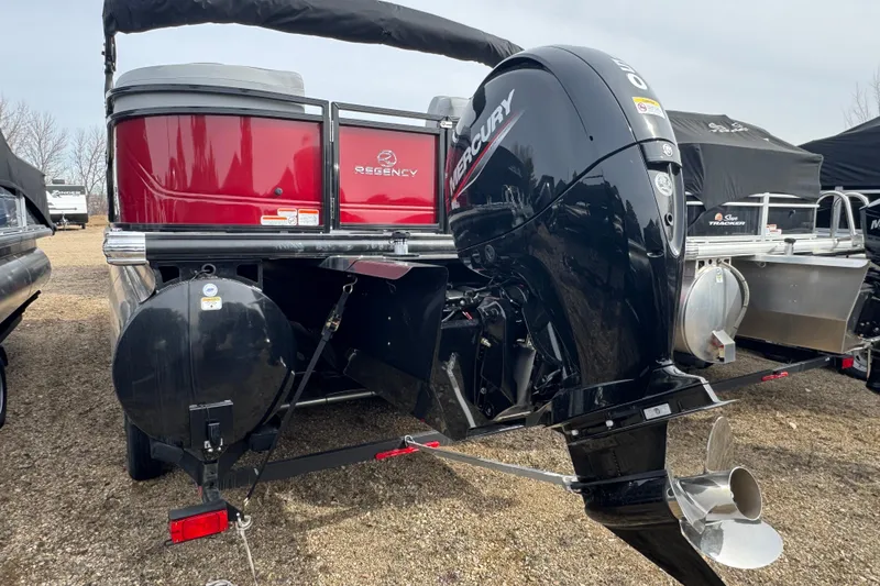 Slide: The Image of 2025 Regency 230 DL3 pontoon boat with Mercury outboard motor, parked on gravel. - 4